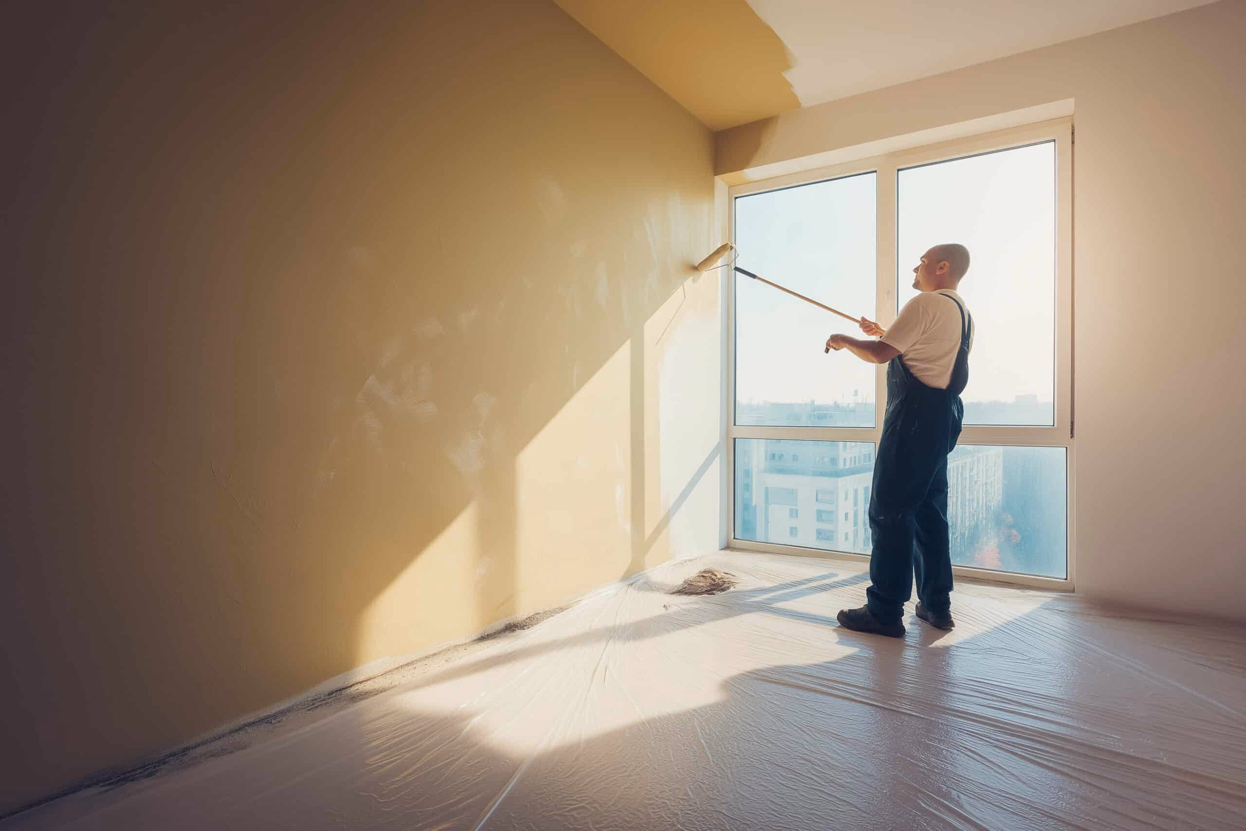 Maler streicht eine Wand in einer hellen Wohnung